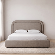 Celeste Curved Upholstered Bed shown in taupe fabric in a bright bedroom – illustrative image – Dune & Pine